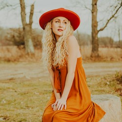 Singer Sophie Dieumente sitting in a meadow